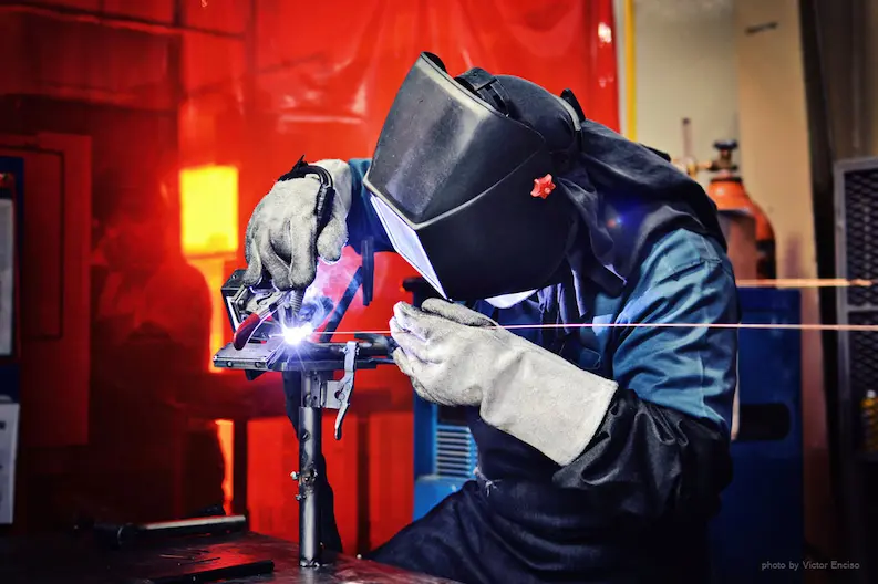 Welder performing TIG welding using argon shielding gas.